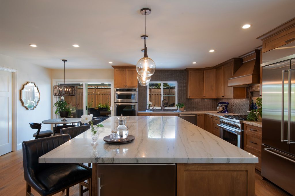 Modern kitchen with large marble island and wooden cabinetry.